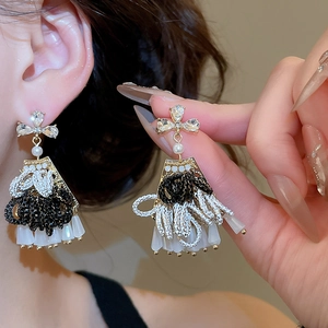 Detailed shot of teardrop fringe earrings with crystal studs and black bead tassels