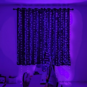Close-up of bright purple LED curtain string lights hanging in a dark indoor setting