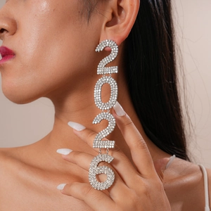 Close-up of sparkling rhinestone-encrusted number 2026 silver drop earrings on model