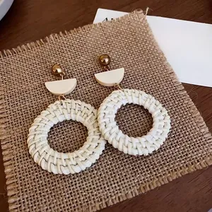 Close-up of bohemian white rattan hoop earrings on rustic burlap background