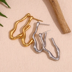 Detailed view of wavy gold and silver stainless steel earrings on a natural background