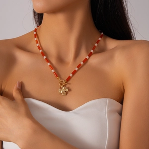 Vintage necklace with red and white glass beads, golden maple leaf pendant, and T-bar clasp