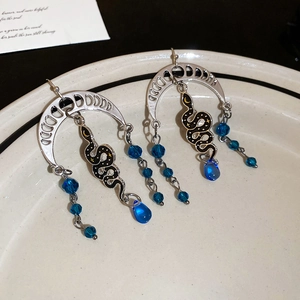 Detail of silver snake earrings featuring crescent moon moonphase and blue teardrop beads
