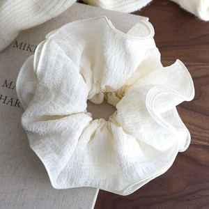 Macro detail of a large white oversized ruffled fabric hair scrunchie with layered texture
