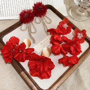 Detailed view of red floral tassel earrings with rhinestones on a vintage wooden tray