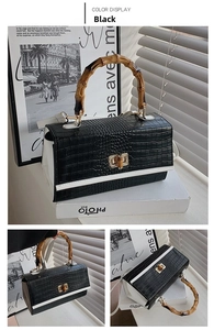 Detail of black crocodile texture bag featuring a vintage bamboo handle and gold twist lock