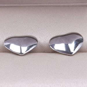 Macro shot of silver heart-shaped stainless steel stud earrings in a beige jewelry box