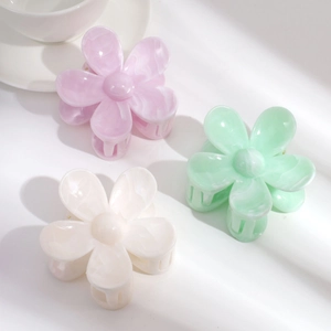 Three gradient acetate flower hair claws in pink, green, and white on a white background