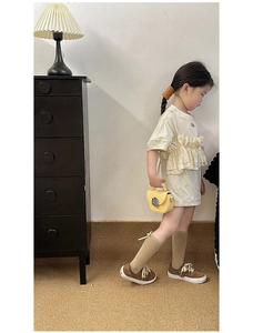 Close-up of beige short-sleeved children's dress with cute ruffled chest detailing