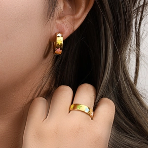 Close-up of gold stainless steel hoop earrings and ring set with colorful star patterns