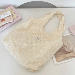 Close-up of beige jacquard tote bag with floral texture and embroidered label details