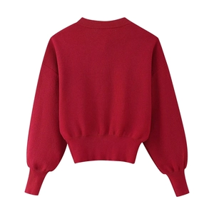 Rear view of red knitted cardigan with ribbed cuffs and waist showing soft texture