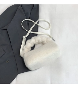 White faux fur handbag detail with woven plush handle and a phone for size reference