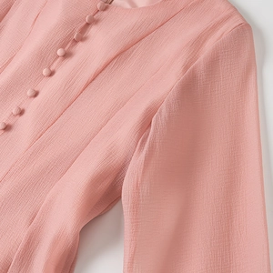 Macro detail of pink chiffon dress featuring elegant fabric-covered buttons and pleated texture