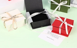 Detailed top view of jewelry gift boxes in white, black, red, and green with silk ribbons