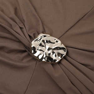 Détail du tissu marron de la robe avec une boucle dorée et des plis élégants