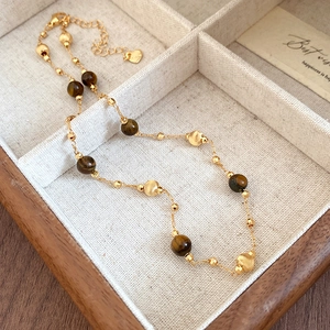 Detail of vintage flower necklace with tiger eye beads and heart pendant on linen