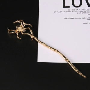 Detailed close-up of a vintage golden spider hair stick with sparkling crystal accents