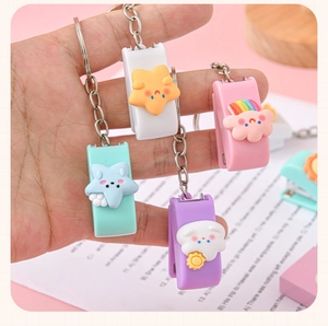 Close-up of four cute cartoon mini stapler keychains in pastel colors for school