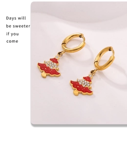Detail of Christmas tree earrings with red enamel and white zircon on golden hoops