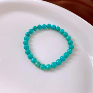 Macro shot of turquoise beads bracelet with brown mineral textures on white ceramic plate