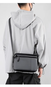 Rear view of model wearing a grey nylon messenger bag with adjustable shoulder strap
