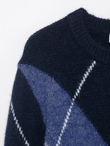 Detail of the crew neck collar and navy blue diamond knit texture of the sweater
