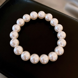 Top view of elegant round white pearl bracelet with high luster on black background