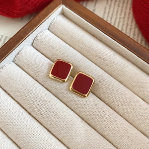 Macro detail of vintage red enamel square stud earrings with elegant gold trim in a gift box