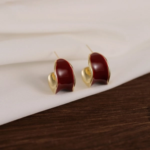 Elegant 18K gold plated C-shaped earrings with deep red glaze on silk and wood background