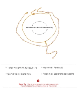 Detail einer mehrlagigen Goldhalskette mit weißen ABS-Perlen und Kreuzanhänger