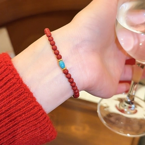 Detailansicht eines roten Achat-Perlenarmbands mit türkisfarbenem Akzent am Handgelenk.