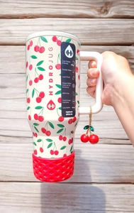 Close-up of cream 40oz tumbler with red cherry pattern and matching charm pendant