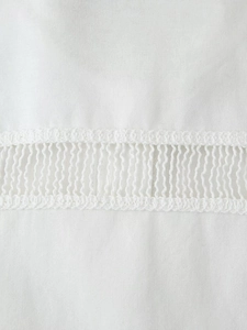 Détail macro du tissu en coton blanc avec une couture en dentelle crochetée exquise