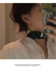 Close-up of minimalist freshwater pearl earring worn with a dark floral silk scarf