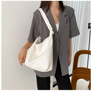 Detailed view of large white minimalist hobo bag with knotted handle on model