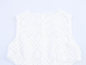Detailaufnahme des weißen Spitzenhäkelmusters an einem ärmellosen Kleid mit Rundhals