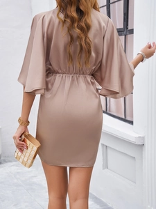 Detail of elegant champagne satin dress featuring bell sleeves and cinched waist on model