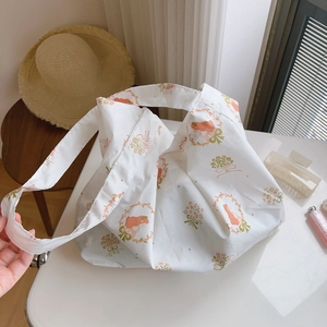 Detailed view of white floral tote bag with cute cartoon girl print on soft cotton fabric