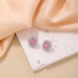 Macro view of pink rectangular gemstone earrings with crystal halo on silk background