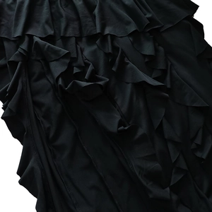 Détail d'une robe noire élégante montrant des volants superposés et une couture précise