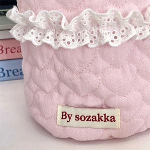 Detail of pink quilted storage basket with heart pattern and delicate white lace trim