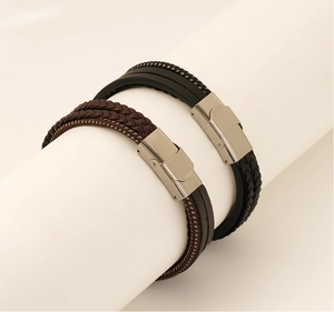Detail of multi-layer braided leather bracelets in black and brown with magnetic clasp