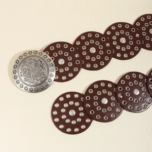 Detail of vintage silver metal buckle with floral engraving on brown western leather belt