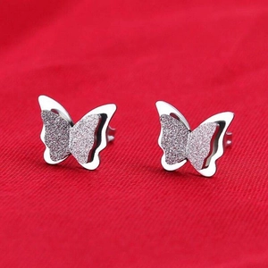 Macro detail of silver butterfly earrings showing layered wings and frosted texture