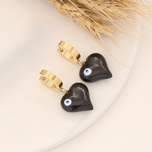 Detail of heart-shaped black earrings with blue evil eye motif and gold clasp