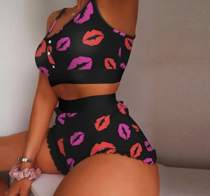 Detail of black camisole pajama set featuring red lip prints and ruffled shorts hem