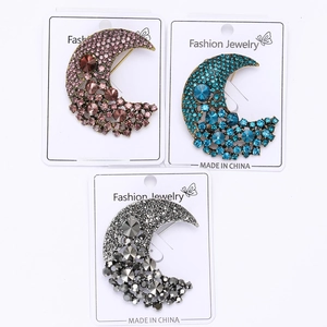 Detailed view of crescent moon brooches with colorful rhinestones on jewelry cards