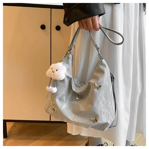 Detail of silver pleated shoulder bag with metal butterfly and plush cloud charm