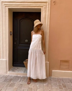Detail shot of a white summer maxi dress featuring minimalist pleated fabric and thin straps